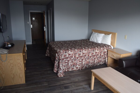 Una habitación de hotel con cama, escritorio, silla y una mesita.
