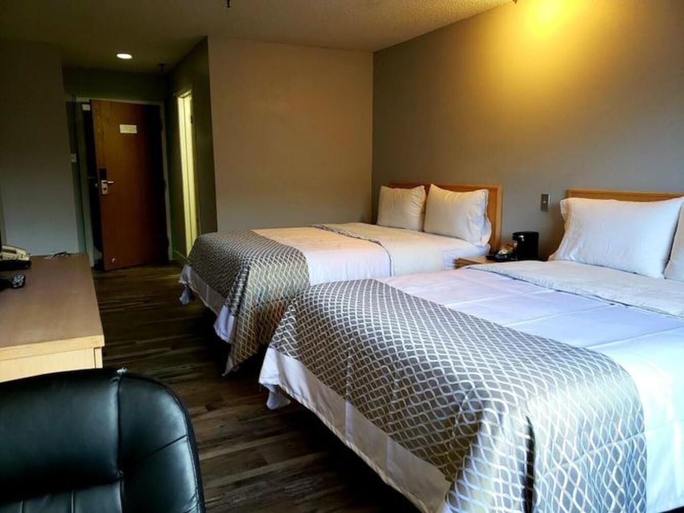 A hotel room with two beds, a desk, and a chair.