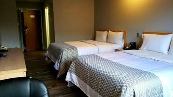 A hotel room with two beds, a desk, and a chair.