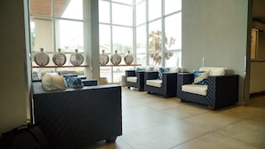 A reception area with large windows, wicker furniture, and decorative spherical lamps.