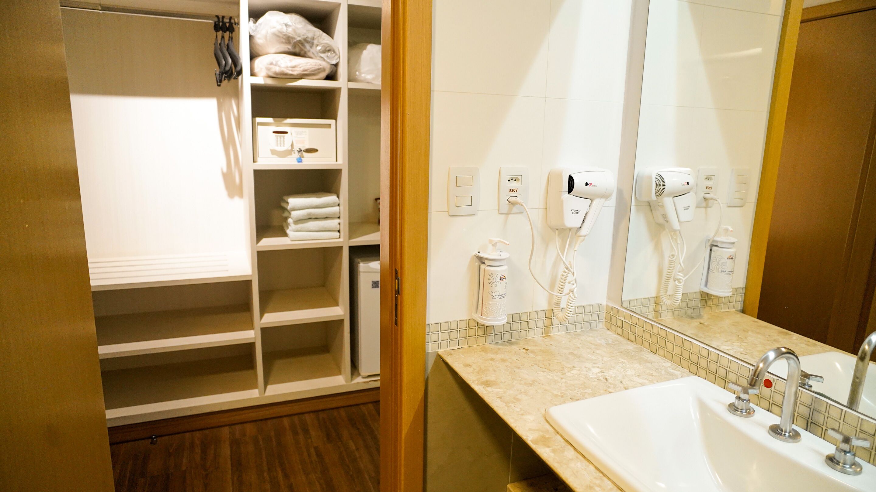 Un bagno d'albergo con un lavandino, due asciugacapelli e un portasciugamani.
