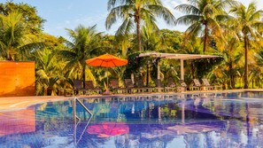 A swimming pool with lounge chairs and umbrellas, surrounded by palm trees. - Hot Beach Celebration (Olímpia)