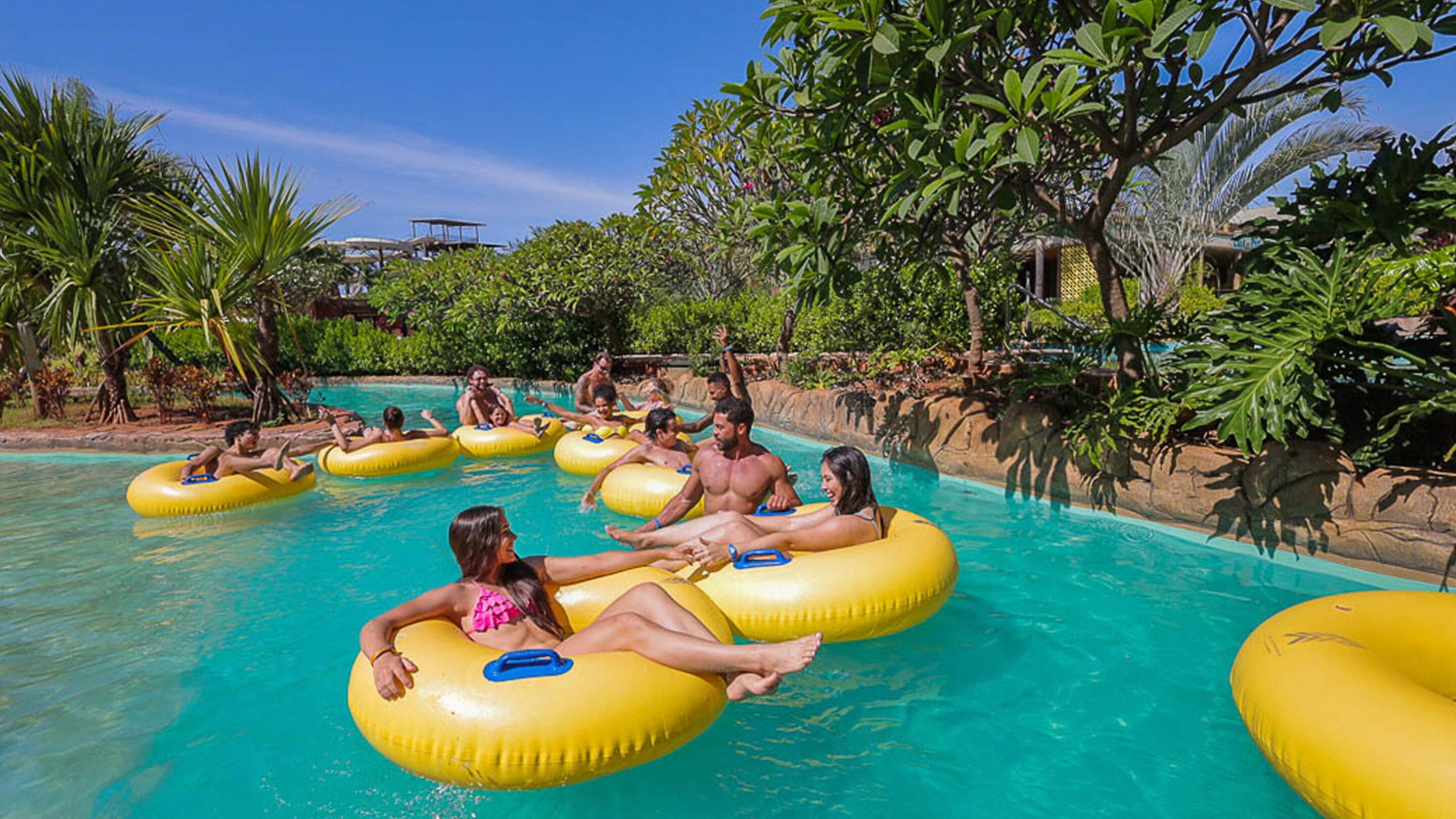 A pool area with people floating on yellow inner tubes.