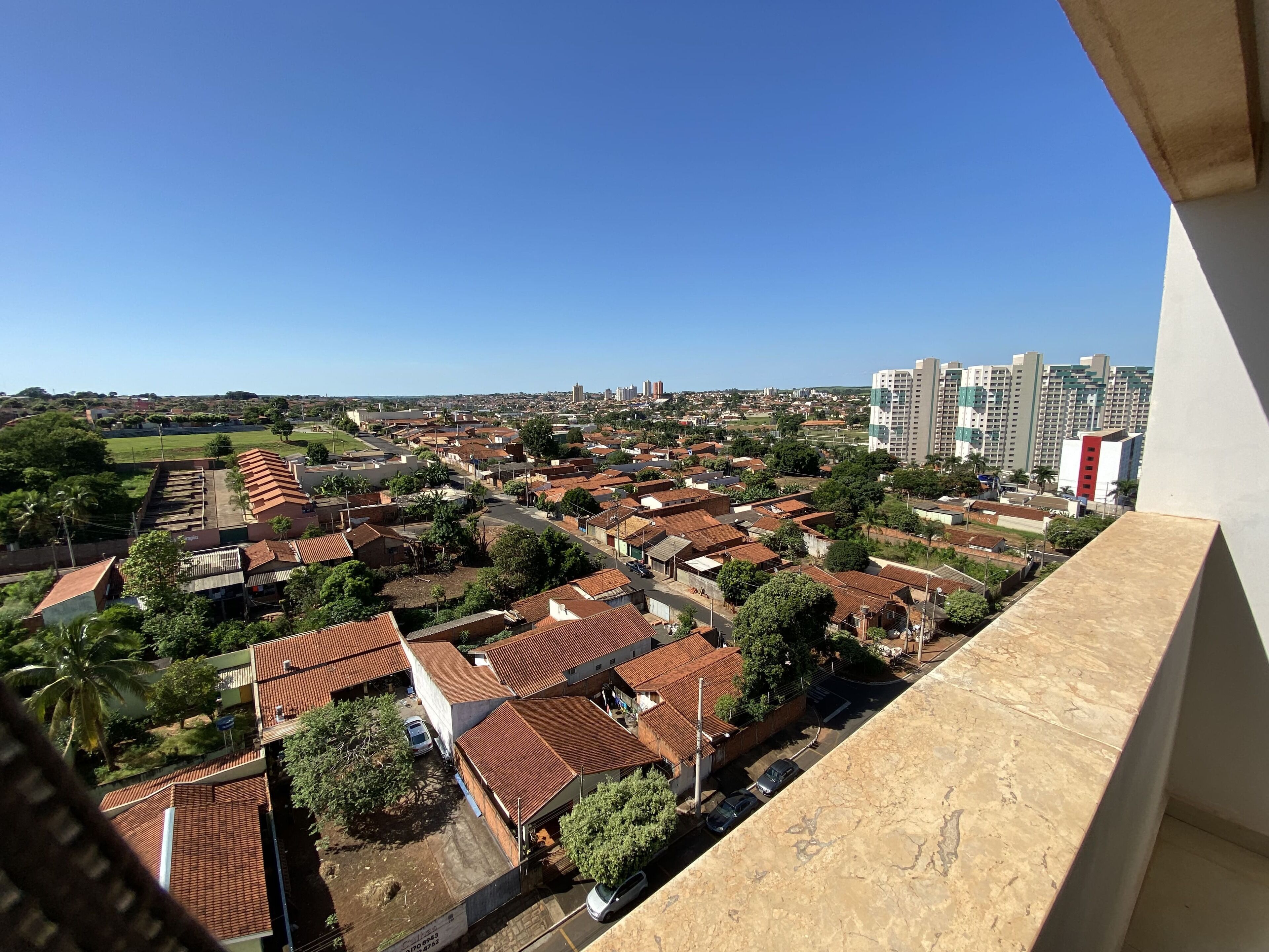 A residential area with red-tiled roofs, a mix of single and multi-story buildings, and a clear blue sky.