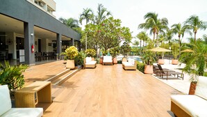 A resort patio with outdoor seating, a pool, and palm trees.