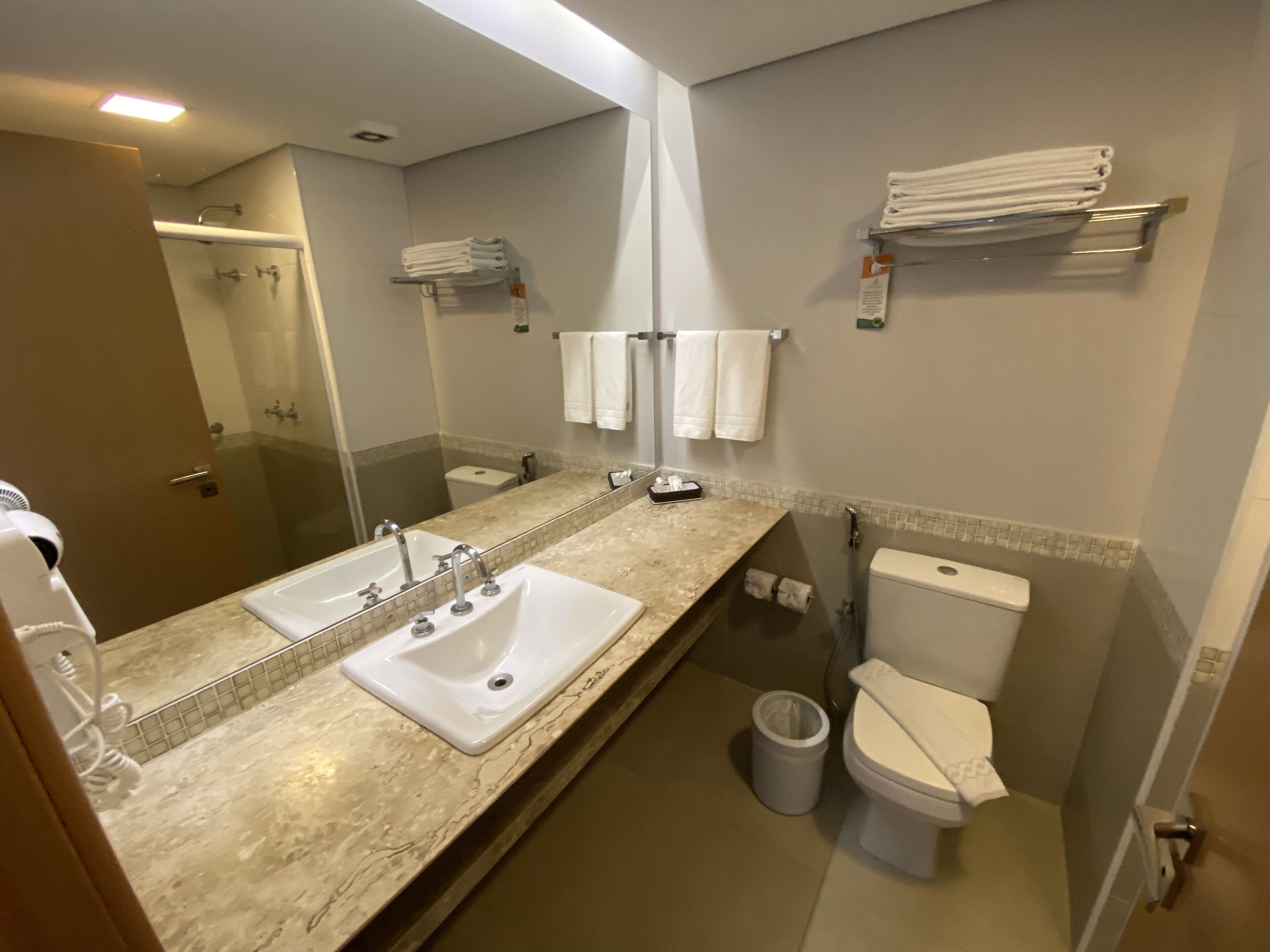 A bathroom with a double sink, a toilet, and a glass shower enclosure.