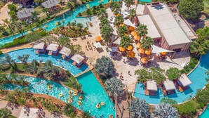A resort with multiple swimming pools, palm trees, and outdoor seating areas.