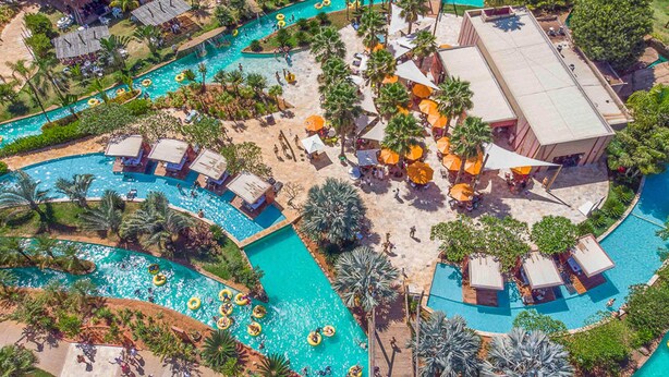 A resort with multiple swimming pools, palm trees, and outdoor seating areas.