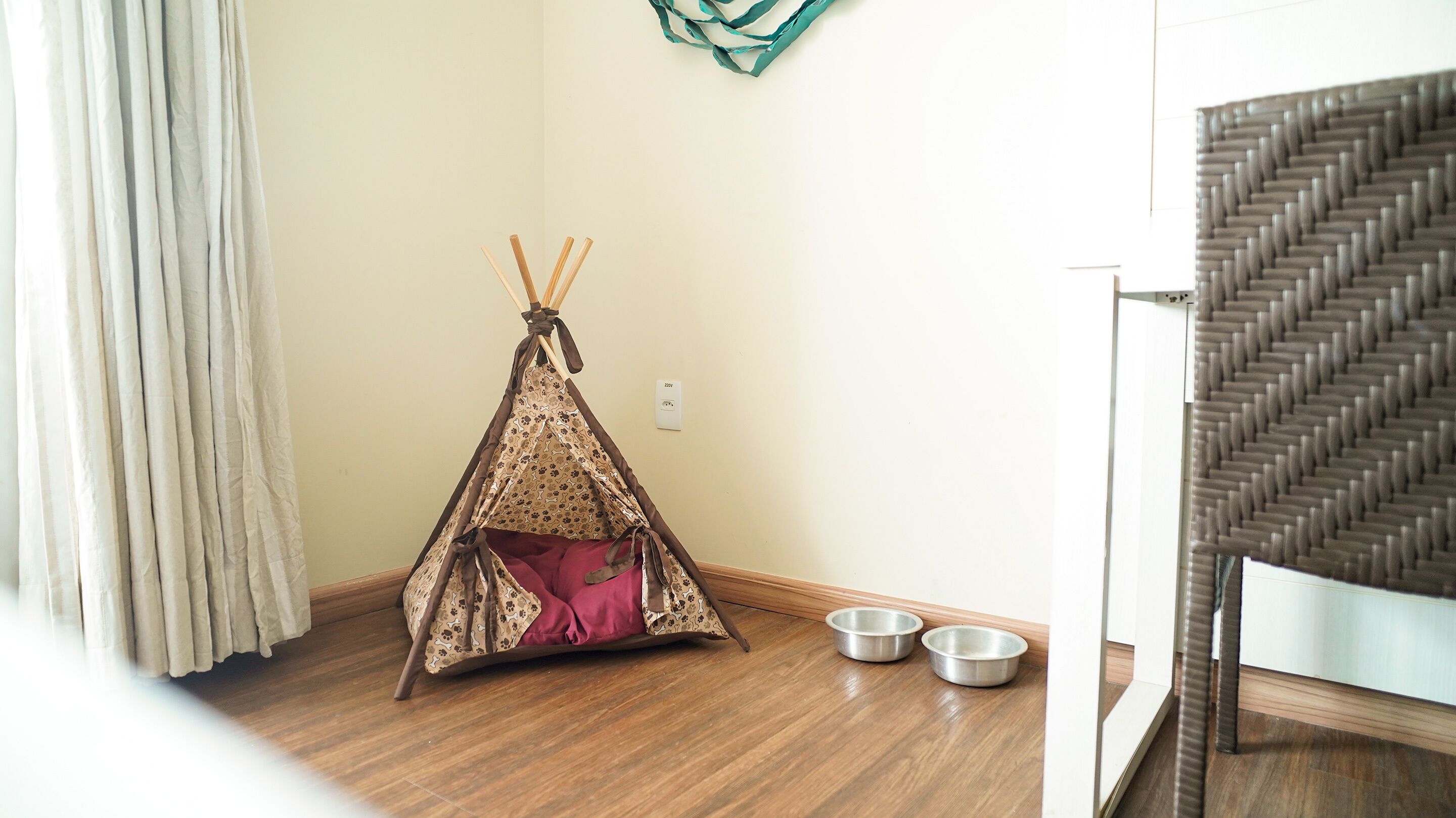 A room with a wooden floor, a small tent-like structure, two metal bowls, and a staircase.