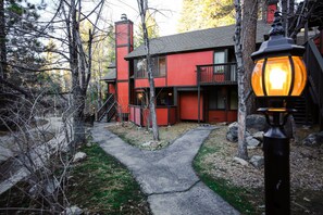 A red building with a black balcony, a chimney, and a stone pathway leading to the entrance.