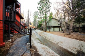 A narrow street with a red building on the left and a green building on the right. A small stream runs down the center of the street.