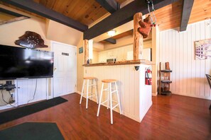 A kitchen with wooden cabinets, a microwave, and a wooden bar counter with stools.
