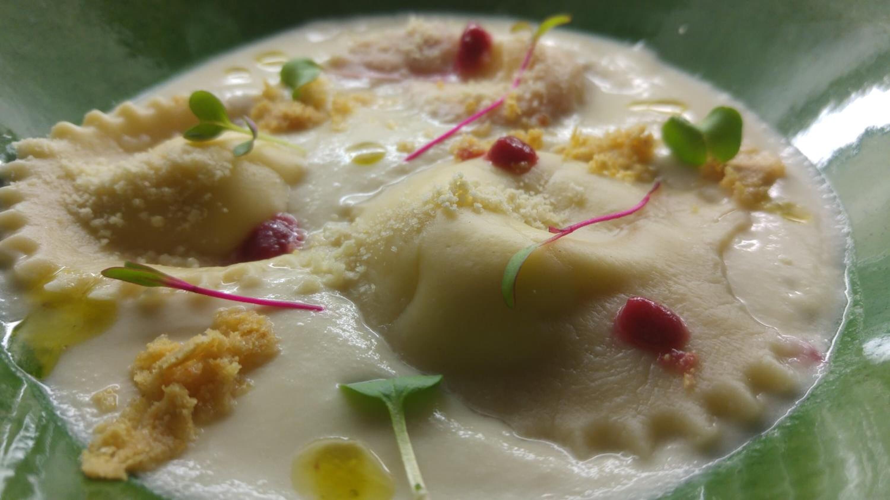 Ein Teller mit Ravioli, Sahne und Garnitur.