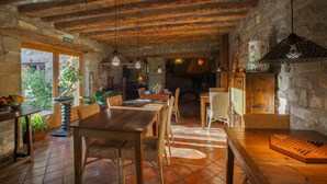 A rustic dining area with wooden tables and chairs, stone walls, and hanging light fixtures. - El Corral de Concilio (Murillo de Gallego)