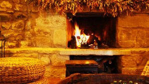 A stone fireplace with a fire, a chessboard, and wicker furniture. - El Corral de Concilio (Murillo de Gallego)
