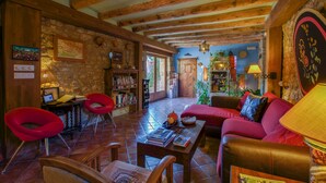 A cozy living room with a fireplace, red chairs, a sofa, and a bookshelf. - El Corral de Concilio (Murillo de Gallego)