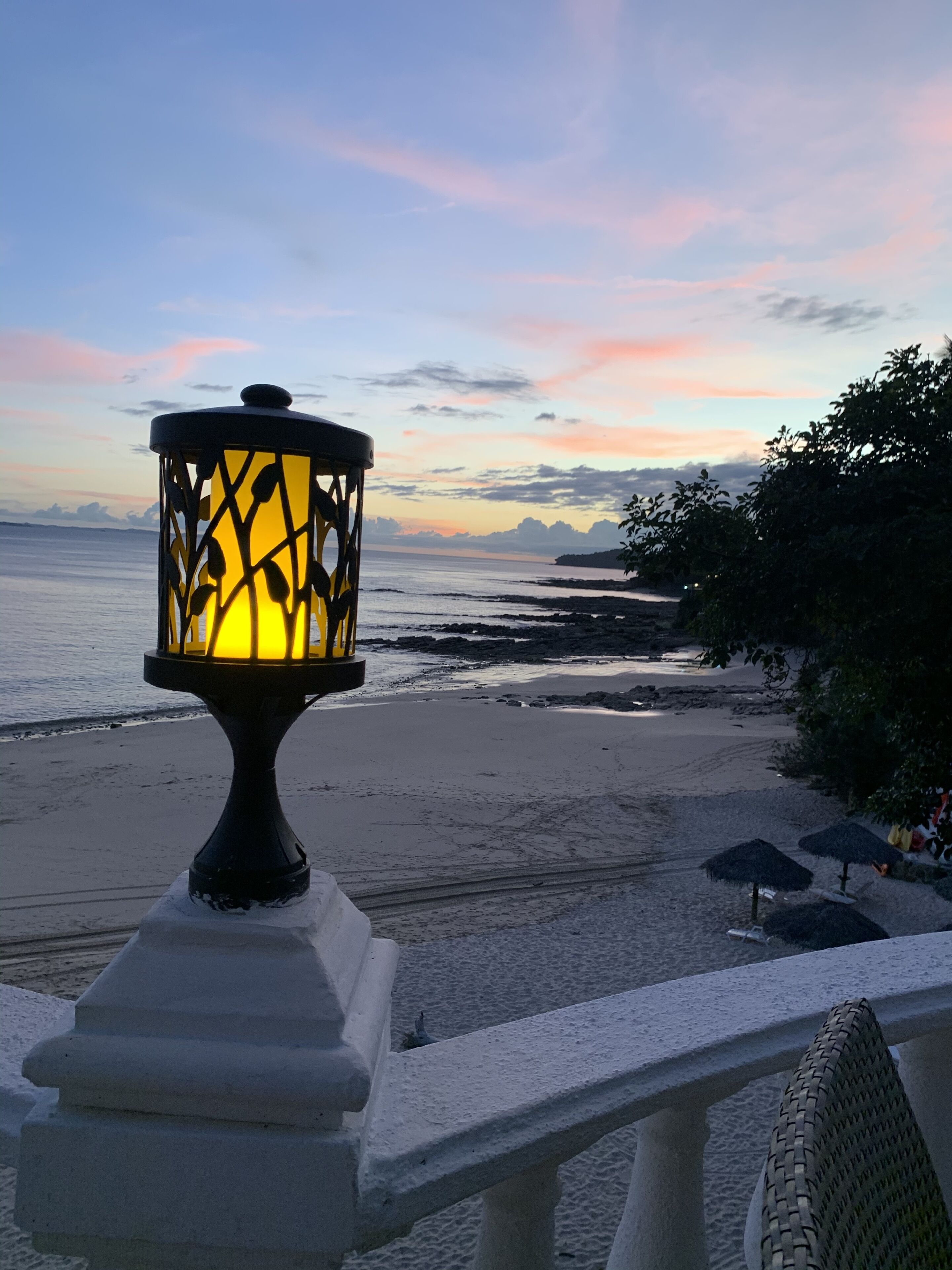 A beach view with a decorative lamp post and a railing.