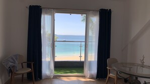 Une pièce avec vue sur la plage, une table ronde et deux chaises.