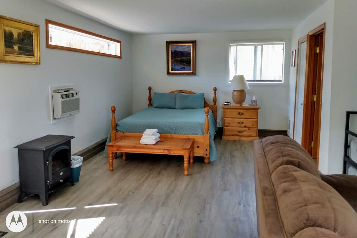 A bedroom with a bed, bedside table, lamp, and a heater.