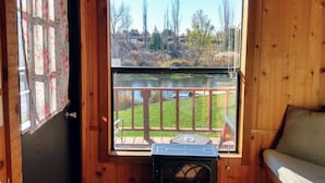 A wooden cabin room with a large window overlooking a grassy area and a body of water. - Billingsley Creek (Hagerman)
