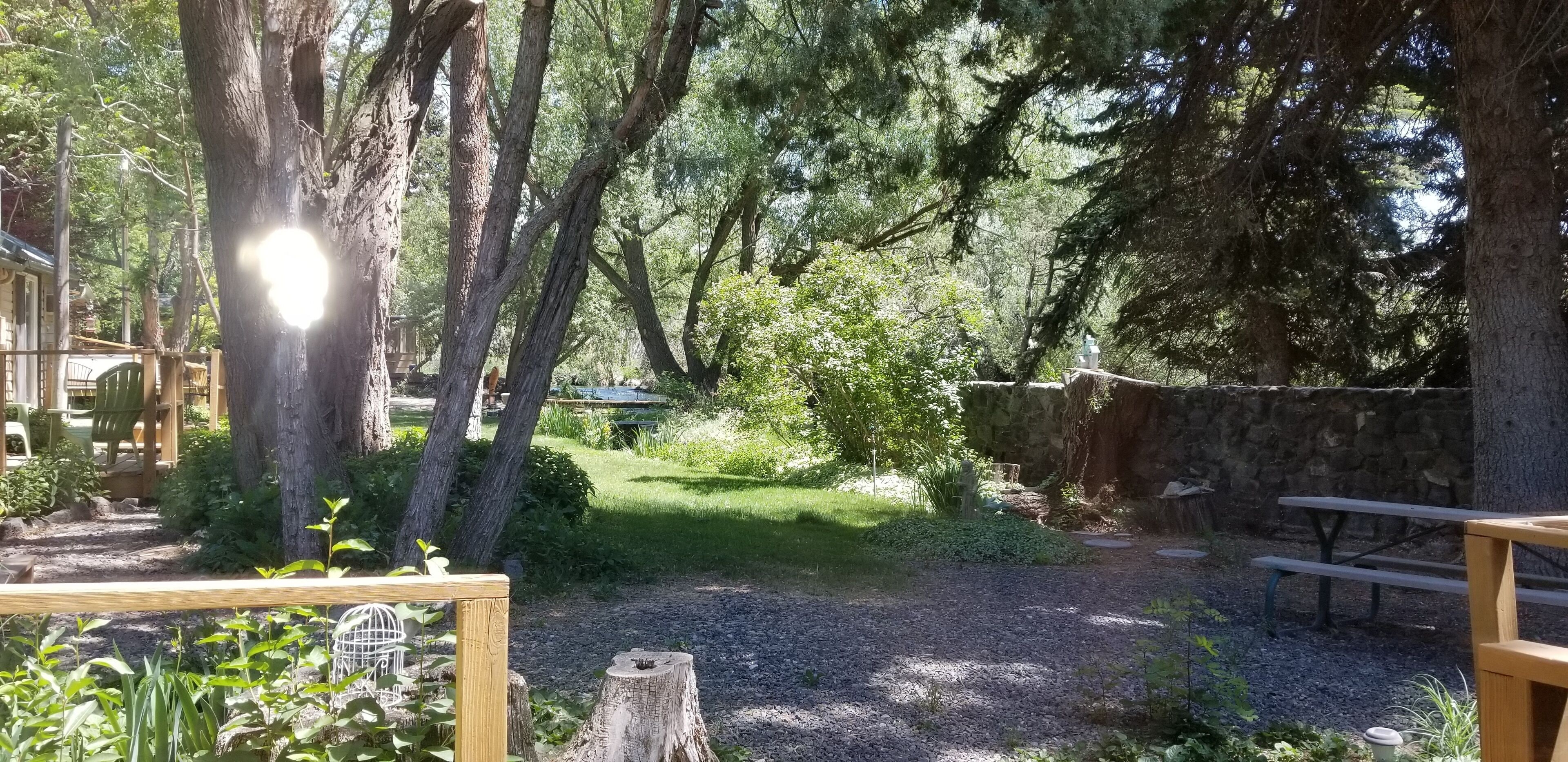 A rustic outdoor area with wooden benches, a stone wall, and a gravel path.