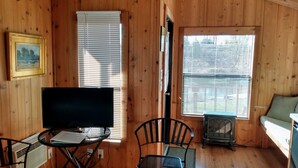 A wooden cabin with a TV on a table, a chair, a heater, and a couch. - Billingsley Creek (Hagerman)
