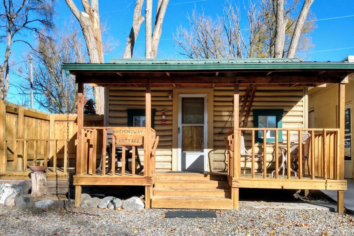 A wooden cabin with a porch labeled "Hemingway Cottage," a door, and a window.