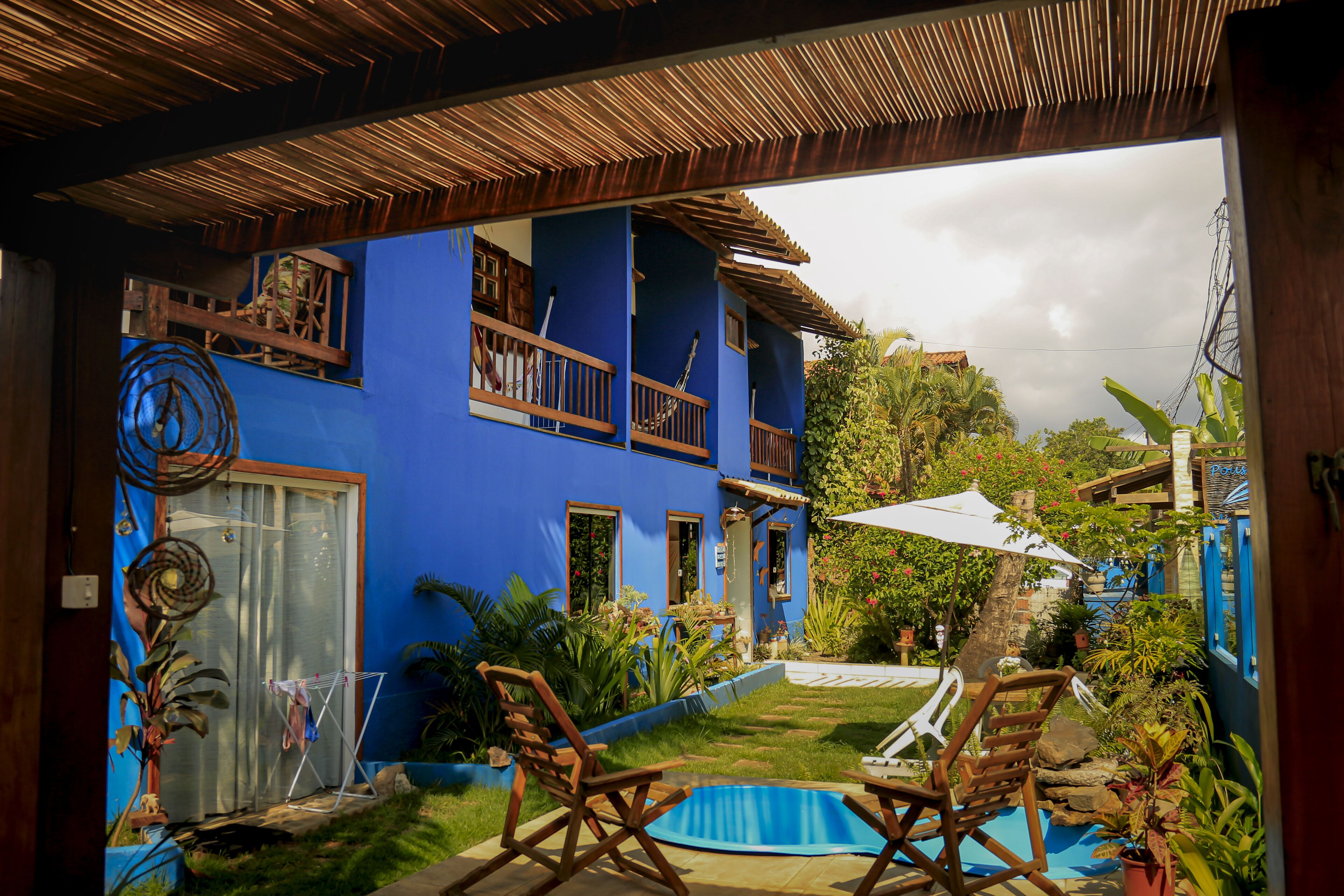 A blue house with a balcony, a small pool, and outdoor furniture.