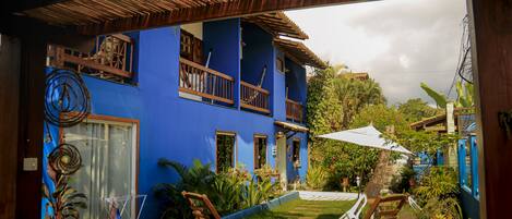 A blue house with a balcony, a small pool, and outdoor furniture.