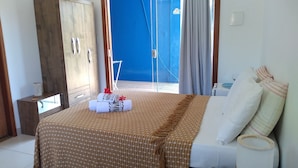 Ein Schlafzimmer mit Bett, Kleiderschrank, einem Fenster mit Vorhängen und Blick auf das Meer.