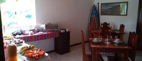 Un comedor con una mesa de buffet, sillas y un cuadro en la pared.