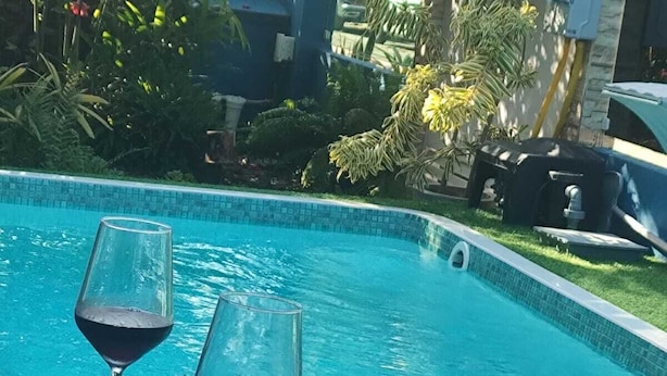 Ein Tisch am Pool mit zwei Weingläsern, einem Dessert und einer Speisenplatte.