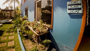 Ein blaues Haus mit Garten, ein Holztisch mit Blumentöpfen und einem Schild, das 'HOME Sweet HOME' zeigt.