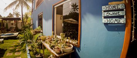 A blue house with a garden, a wooden table with potted plants, and a sign that reads "HOME Sweet HOME".