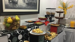 A buffet table with various food items, a fruit bowl, and a framed picture on the wall. - Hotel Corbel (Mar del Plata)