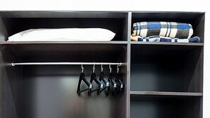 A dark wooden closet with a hanging rack, shelves, and a safe. - Hotel Corbel (Mar del Plata)