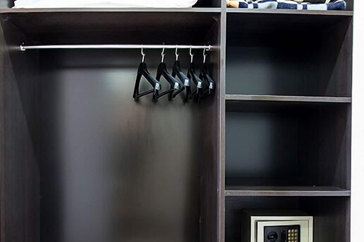 A dark wooden closet with a hanging rack, shelves, and a safe.
