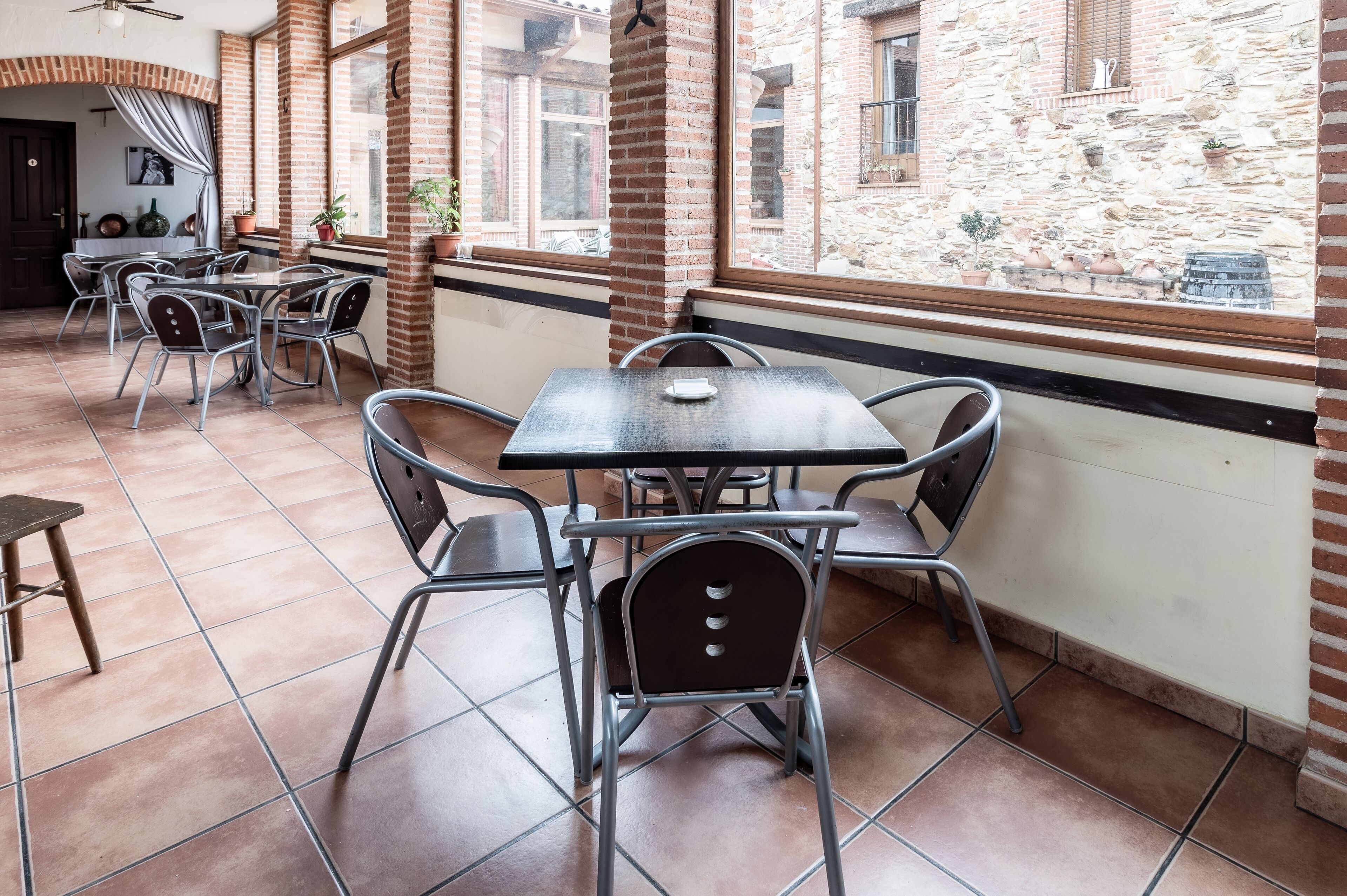 A café with metal tables and chairs, brick walls, and large windows.