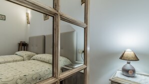 A bedroom with a bed, a nightstand, a lamp, and a mirror reflecting the room. - Hotel Rural VII Carreras by Vivere Stays (San Pedro de Rozados)