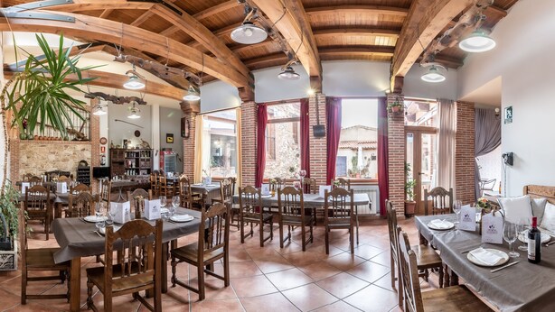 A restaurant with wooden beams, brick walls, and tiled floors. Tables are set with wine glasses and menus. - Hotel Rural VII Carreras by Vivere Stays (San Pedro de Rozados)