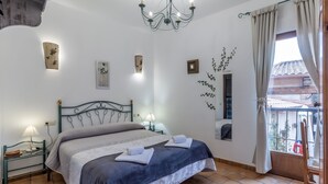 A bedroom with a bed, a nightstand, a lamp, a chandelier, and a window with curtains. - Hotel Rural VII Carreras by Vivere Stays (San Pedro de Rozados)