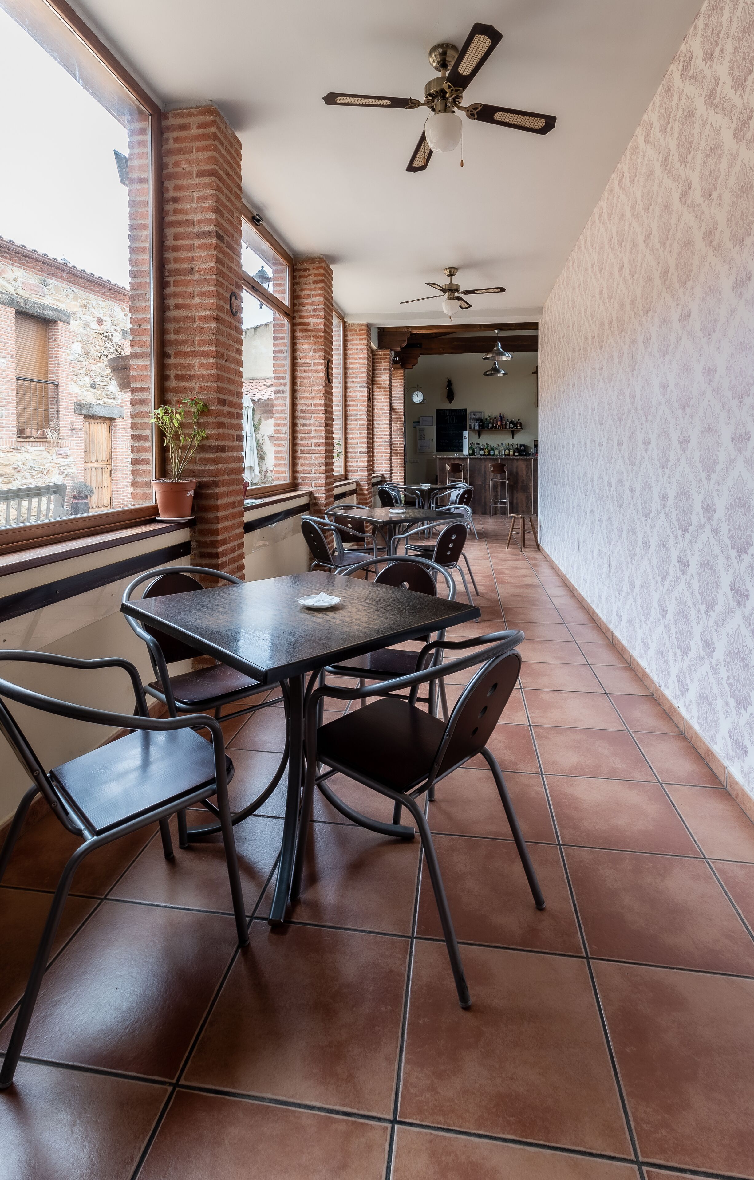 A restaurant with brick walls, large windows, and tiled flooring.