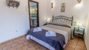 Un dormitorio con cama, mesita de noche, espejo y estante en la pared.