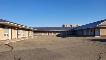 A building with multiple rooms, a parking lot, and a clear sky.