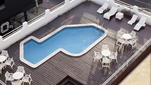 A deck with a swimming pool, lounge chairs, and tables. - JB Hotel (Petrolina)