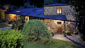 A stone house with a covered patio and a stone fireplace. - Casa Rural O Vilar (Ortigueira)