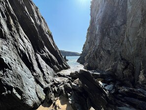 A rocky coastal landscape with steep cliffs and a narrow passage leading to the sea. - Casa Rural O Vilar (Ortigueira)