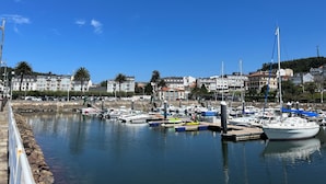 A marina with boats docked, surrounded by buildings and palm trees. - Casa Rural O Vilar (Ortigueira)