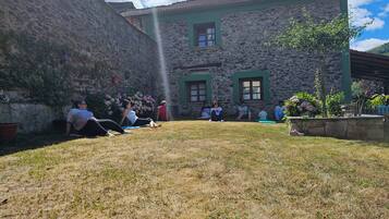 Un edificio de piedra con fachada verde y un patio cubierto de césped.
