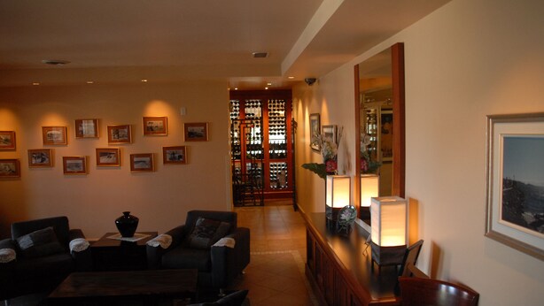 A hotel lobby with a seating area, a reception desk, and a wine rack. - Hôtel Mingan (Sept-Iles)